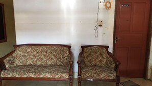 Ein Zimmer mit zwei Holzdavonzügen mit floralem Bezug, einer roten Tür und einer Steckdose.