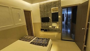 Een moderne hotelkamer met een groot bed, een ingebouwde televisie, een spiegel en een badkamer met douche.