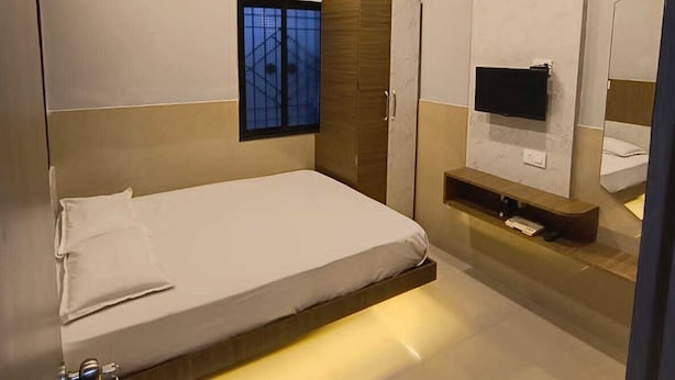 Een moderne slaapkamer met een bed, een televisie en een raam.