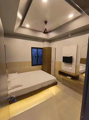 A modern bedroom with a bed, a TV, and a window. - Prerna Cottage & Lodge By GRB (Solapur)