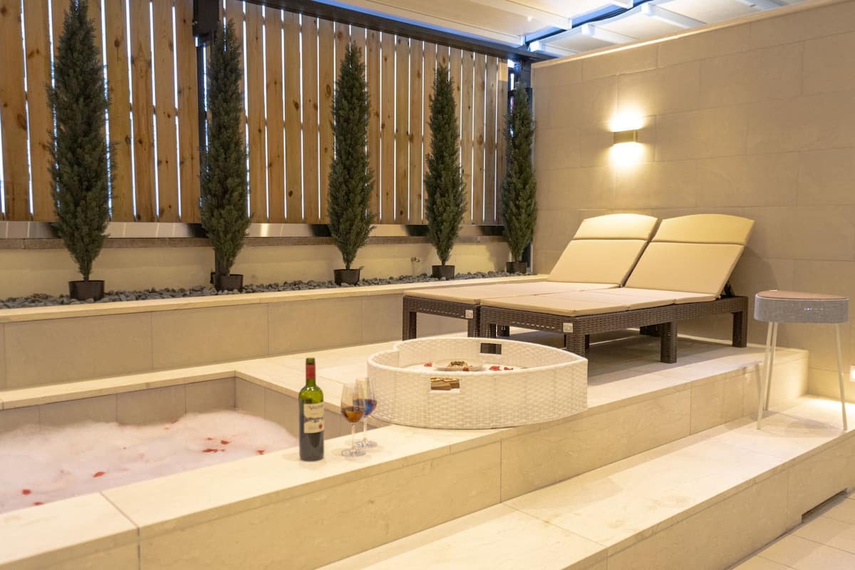 Un espace bien-être comprenant un bain à remous, un fauteuil de relaxation et trois arbres en pot.