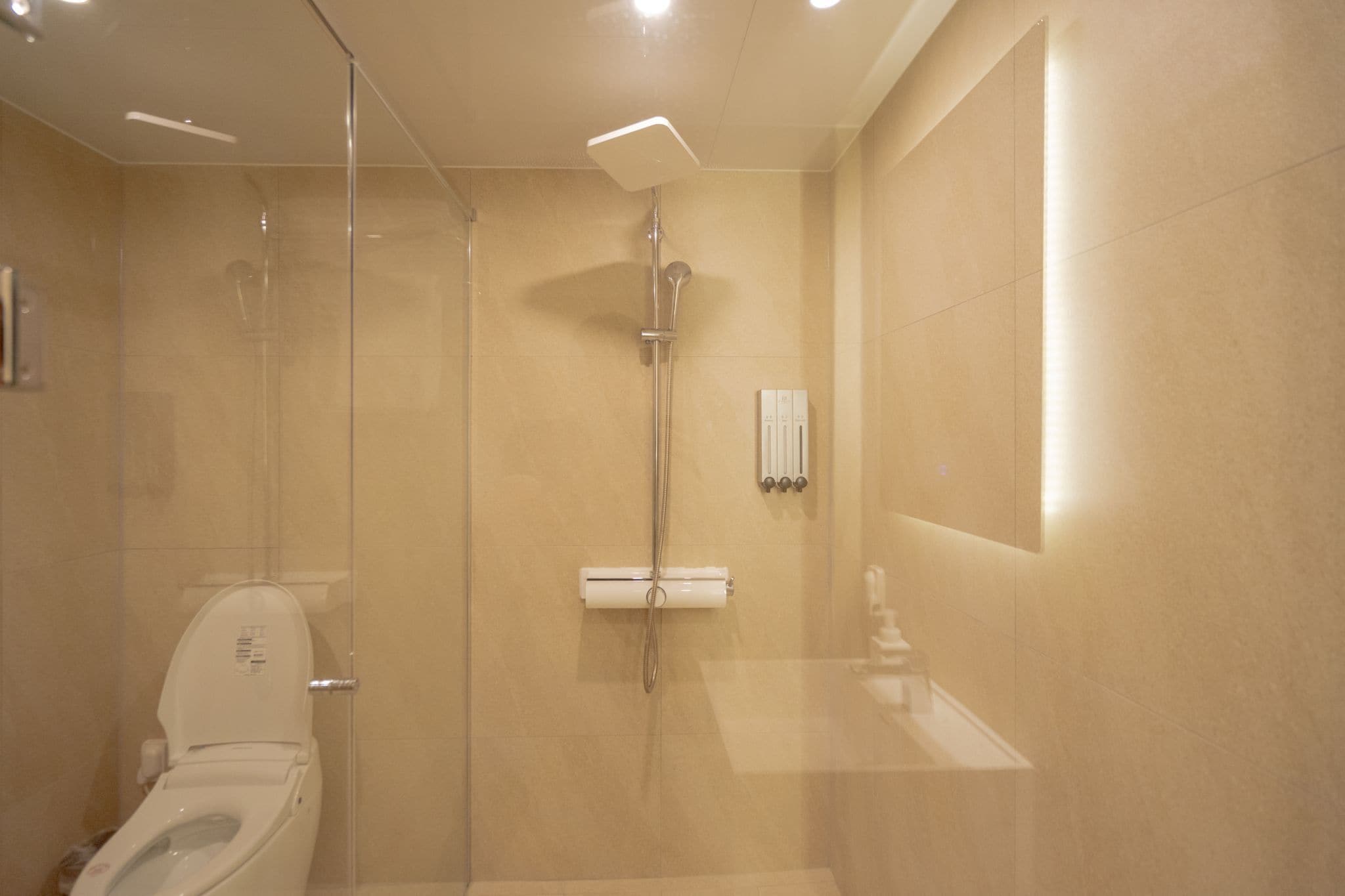 A modern bathroom with a glass-enclosed shower, a toilet, and a sink.