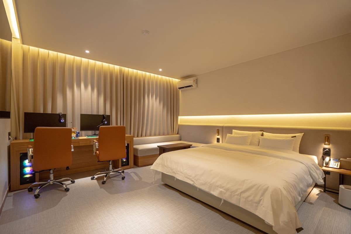 Une chambre d’hôtel avec un grand lit, un bureau avec deux chaises, un canapé et un téléviseur.