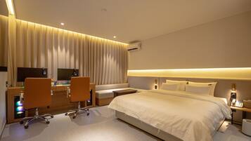 Una habitación de hotel con una cama grande, un escritorio con dos sillas, un sofá y una televisión.