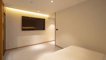 A modern hotel room with a large bed, a built-in bench, and a wall-mounted TV.
