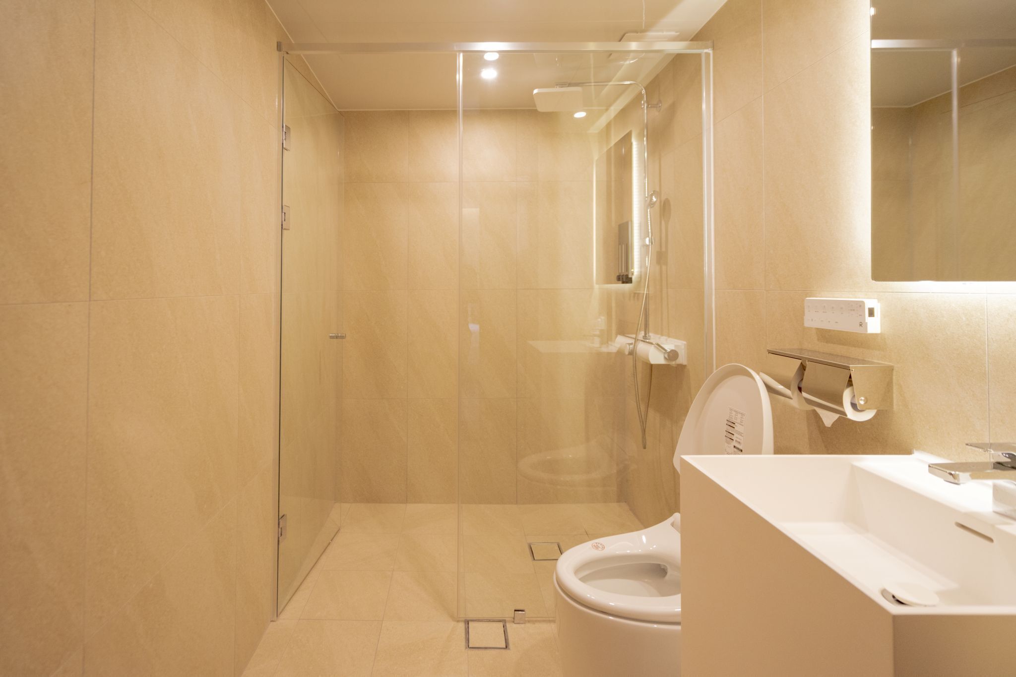A modern bathroom with a glass-enclosed shower, a toilet, and a sink.