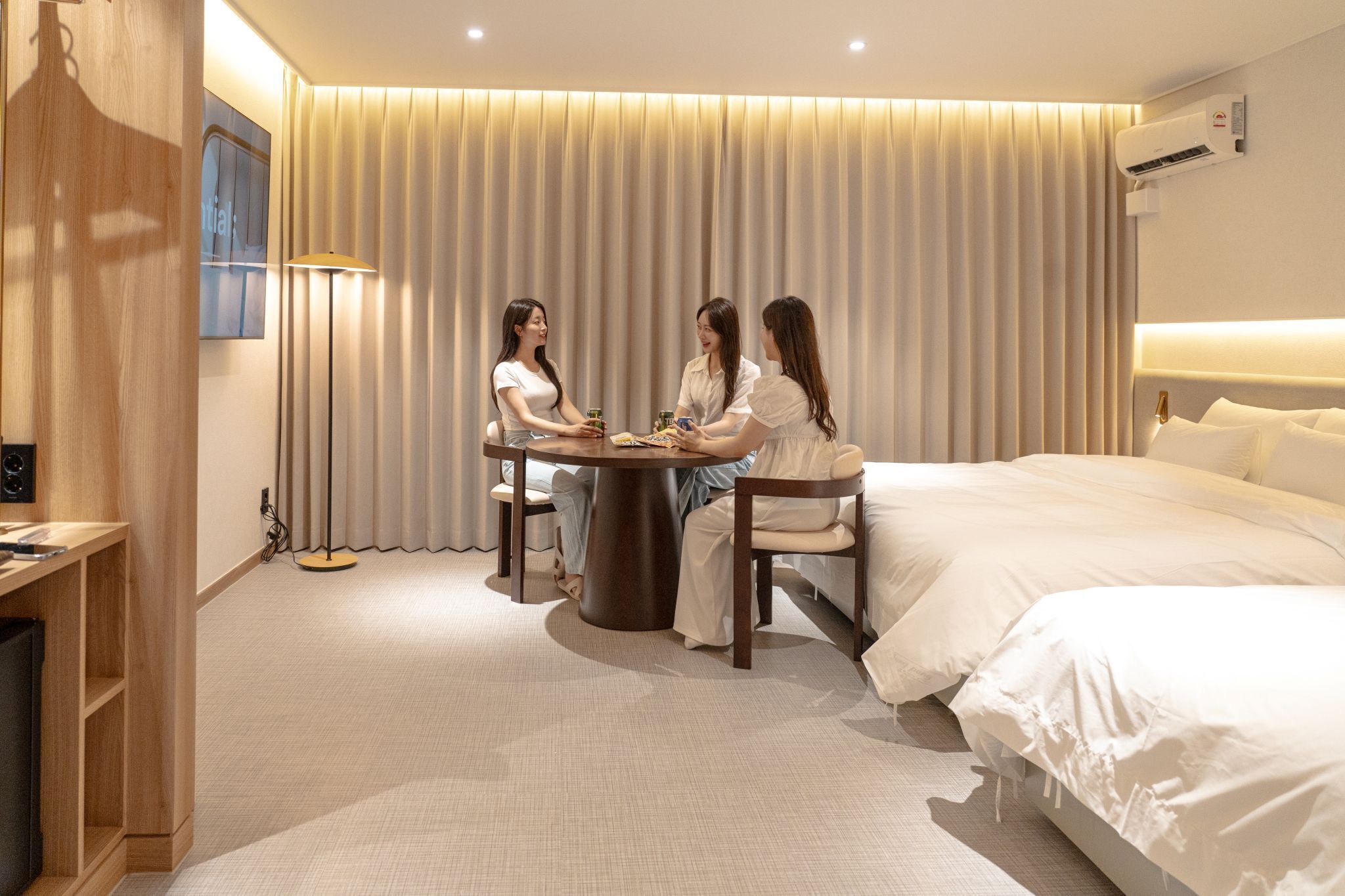 Una habitación de hotel con una cama grande, una mesa redonda con sillas y una lámpara.