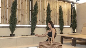 A woman sitting by a poolside area with a wicker basket and a white chair. - H-AVENUE Hotel Gwangju Cheomdan (Gwangju)