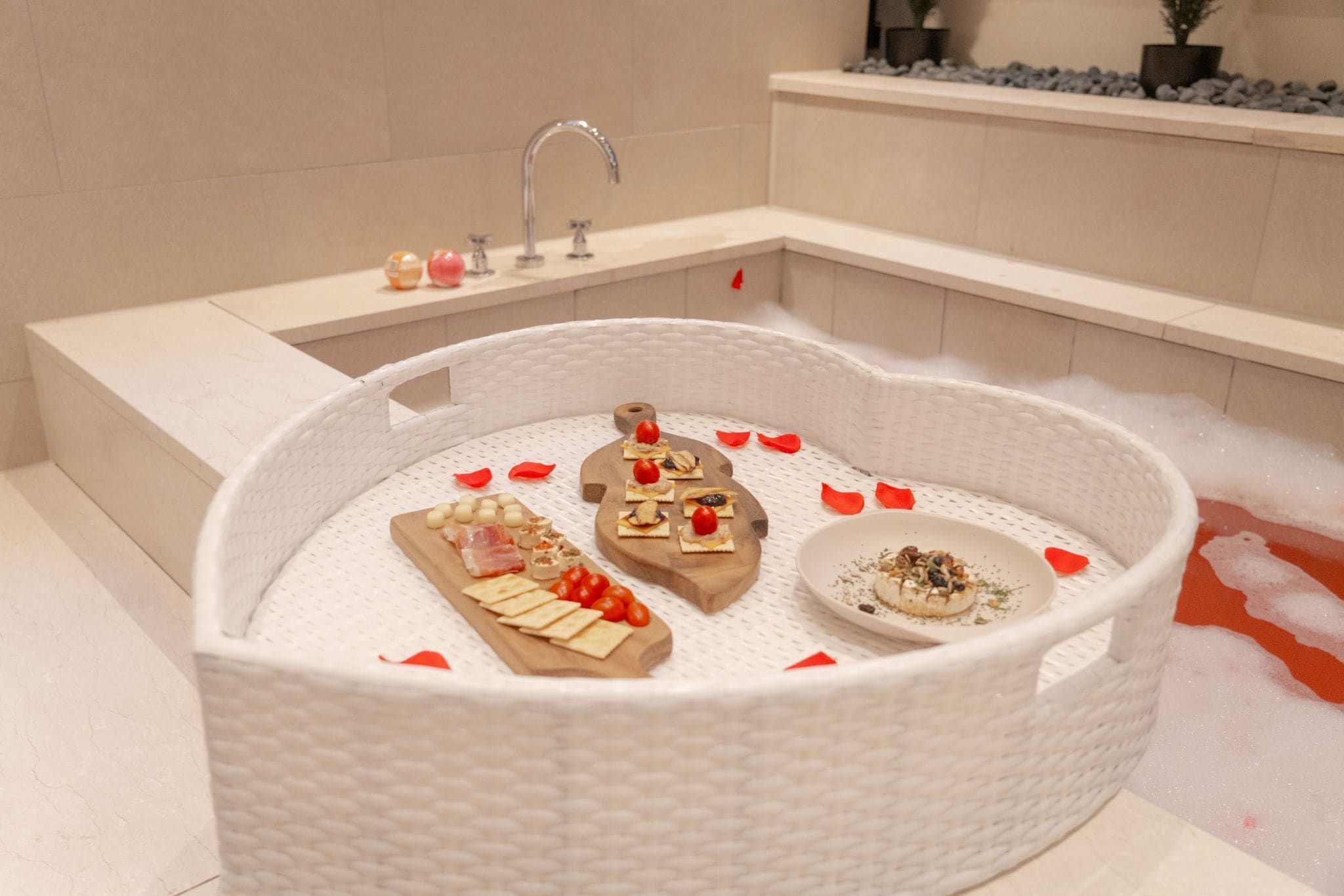 Una bañera con una bandeja de madera que sostiene bocadillos y un recipiente pequeño de comida.