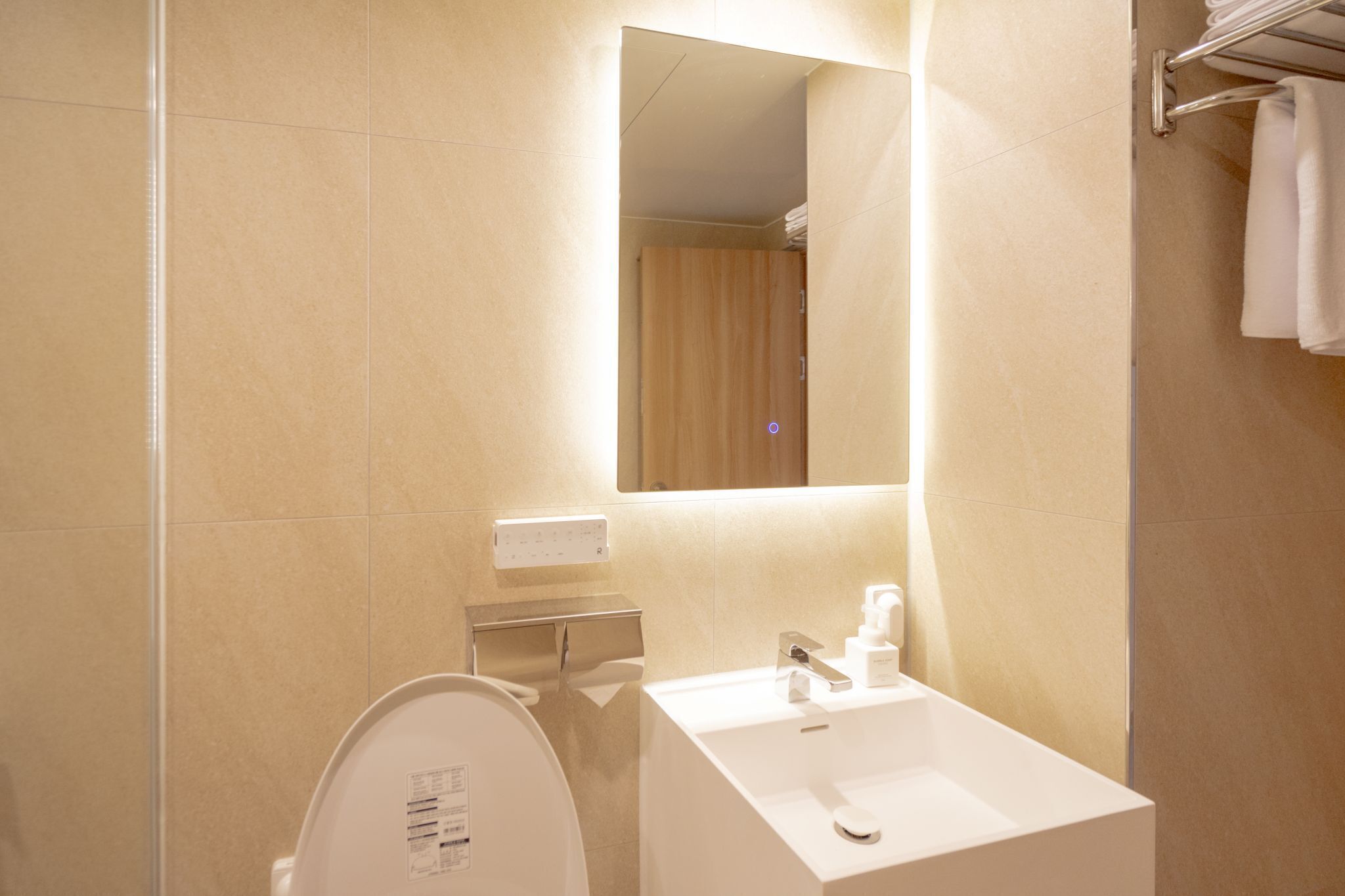 Un baño moderno con un lavamanos blanco, un espejo y un inodoro.