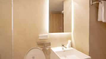 Un baño moderno con un lavamanos blanco, un espejo y un inodoro.