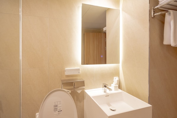 Un baño moderno con un lavamanos blanco, un espejo y un inodoro.