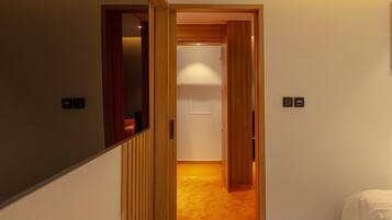 A hallway with wooden doors leading to a room with a carpeted floor.