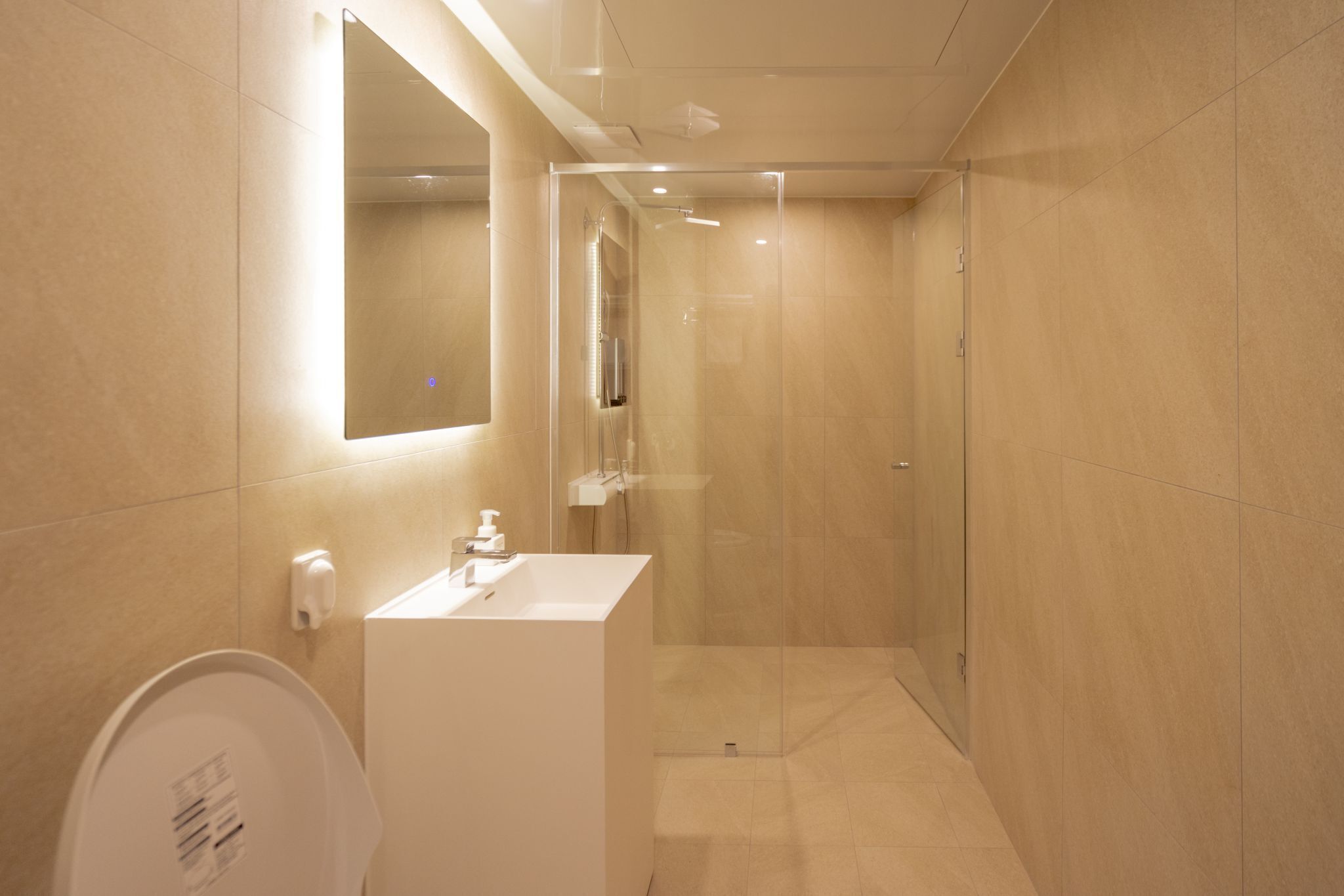 A modern bathroom with a glass-enclosed shower, a white sink, and a large mirror.
