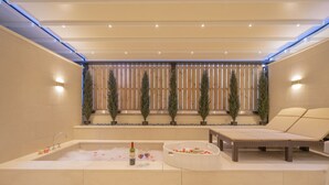 A modern spa area with a large bathtub, a lounge chair, and a wooden fence with potted plants. - H-AVENUE Hotel Gwangju Cheomdan (Gwangju)