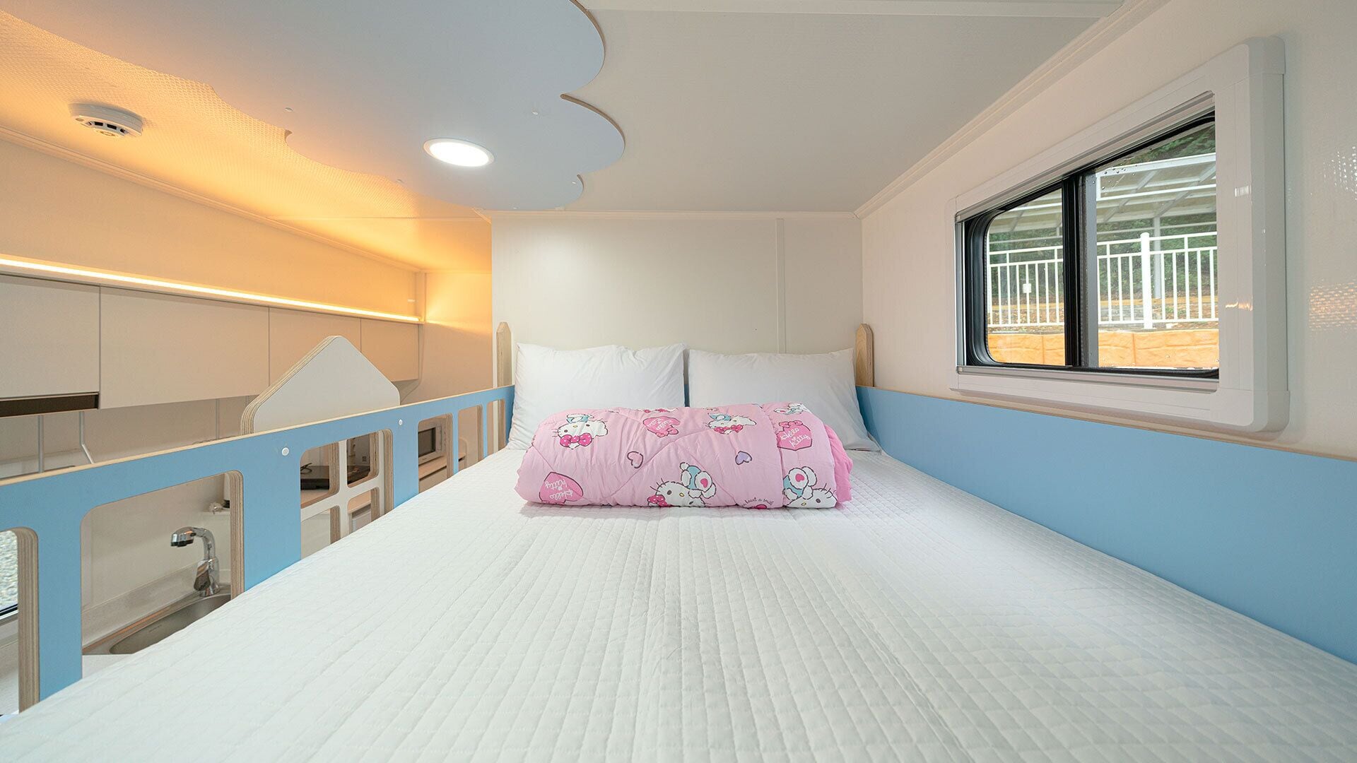 A bedroom with a bunk bed, a window with a view, and a ceiling with recessed lighting.
