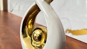 A white ceramic sculpture with a gold finish on a wooden surface. - LivLuxe Apartments 2 (Kampala)