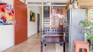 Un couloir avec un banc en bois, un réfrigérateur et un petit tabouret.