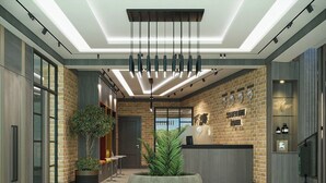 Et moderne receptionsområde med et centralt siddeområde, en reception og en murstensvæg med et ur.