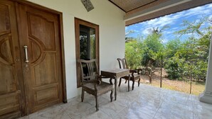A wooden door, a window, a wooden chair, a wooden table, and a tiled floor. - Hotel O Gunung Mas Homestay (Pemuteran)