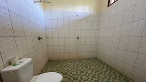 A small, tiled bathroom with a toilet, a shower, and a checkered floor pattern. - Hotel O Gunung Mas Homestay (Pemuteran)