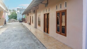Ένας διάδρομος με πλακάκια στο δάπεδο, ο οποίος οδηγεί σε ένα κτίριο με πολλές πόρτες και παράθυρα.