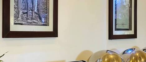A buffet setup with stacked plates, a food station, and two framed pictures on the wall.