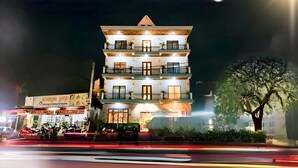 Een hotel met meerdere verdiepingen, balkons en een goed verlichte ingang.