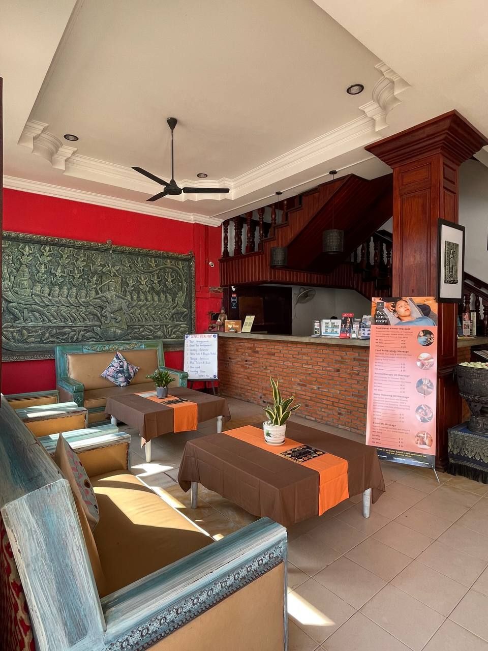 A lobby with a red wall, a wooden reception desk, and a seating area with sofas and tables.