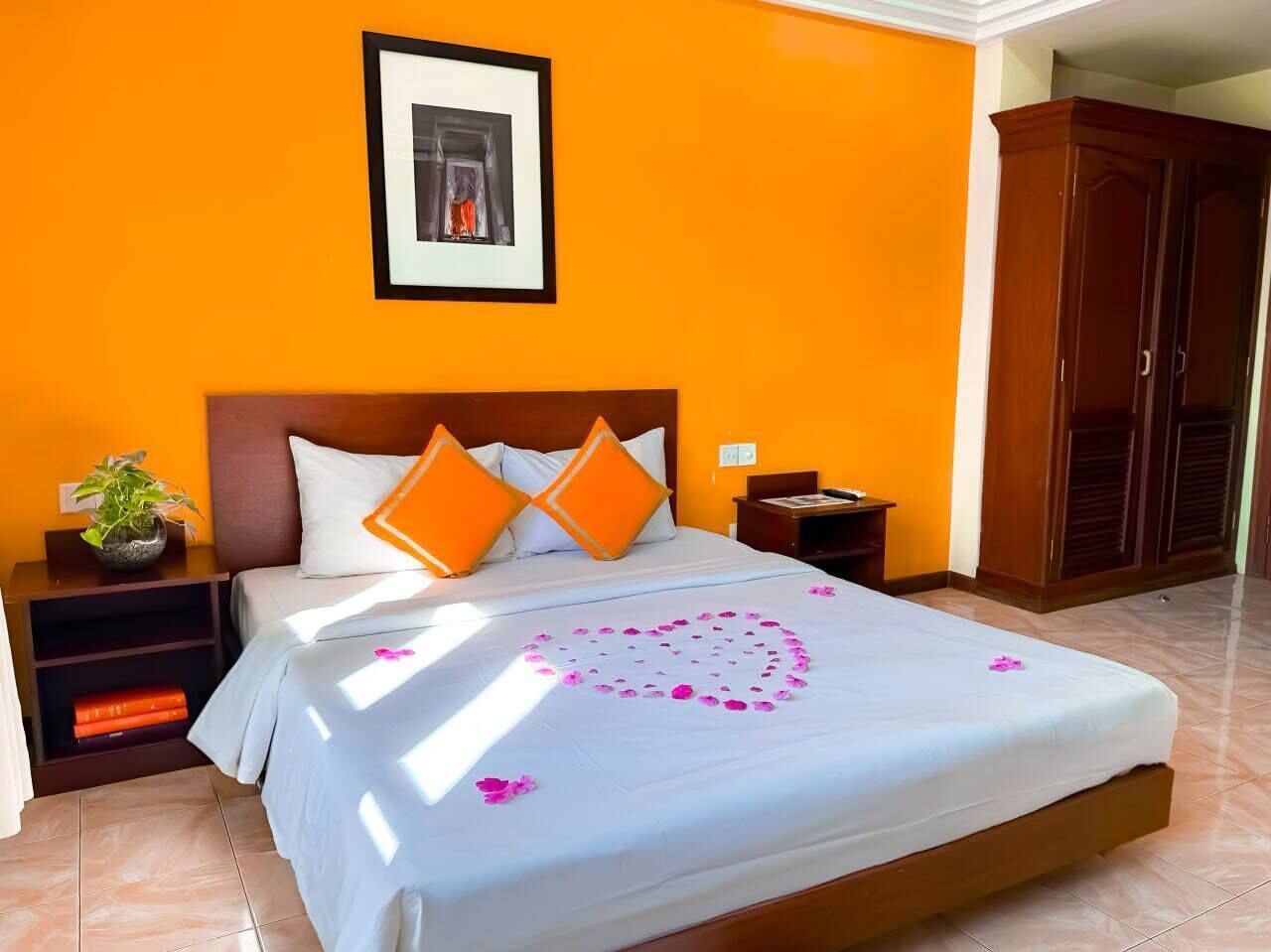 Ein Hotelzimmer mit Bett, orangefarbenen Wänden, einem gerahmten Bild an der Wand und einem Kleiderschrank.