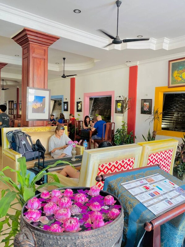 A hotel lobby with a seating area, a decorative water feature with lotus flowers, and framed artwork on the walls. - VPlus Hotel (Siem Reap)