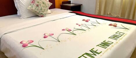 A neatly made bed with a floral arrangement and a welcome message.