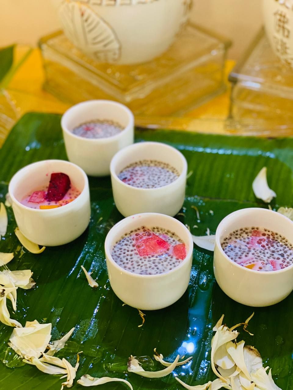 A table with four small bowls of dessert on a banana leaf.