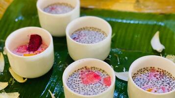 A table with four small bowls of dessert on a banana leaf.