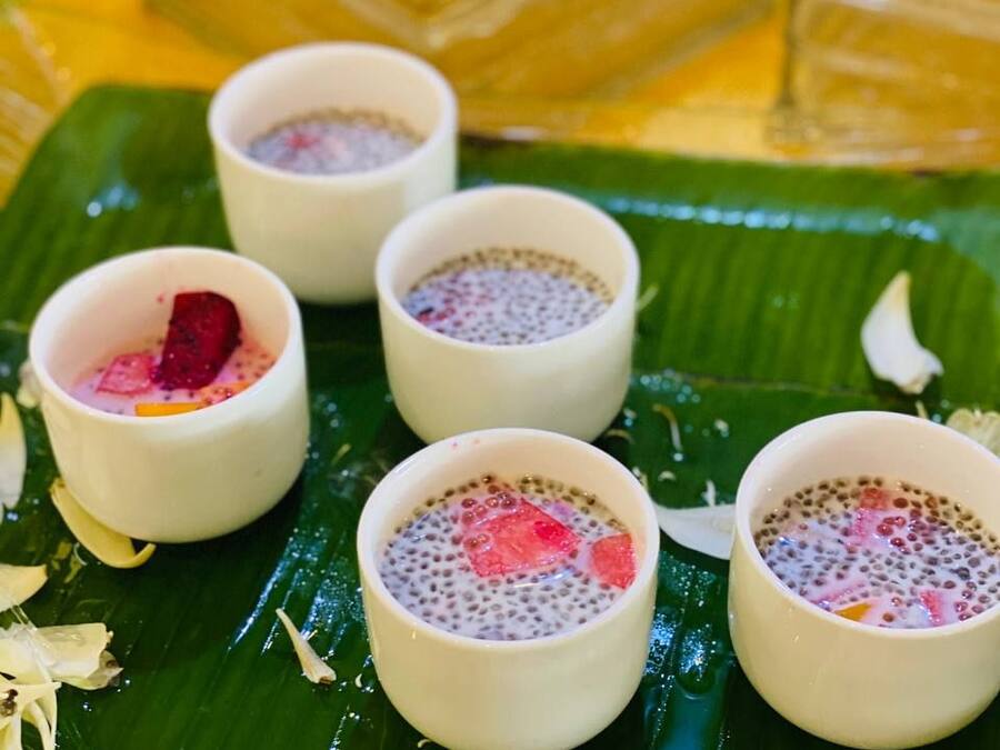 A table with four small bowls of dessert on a banana leaf.
