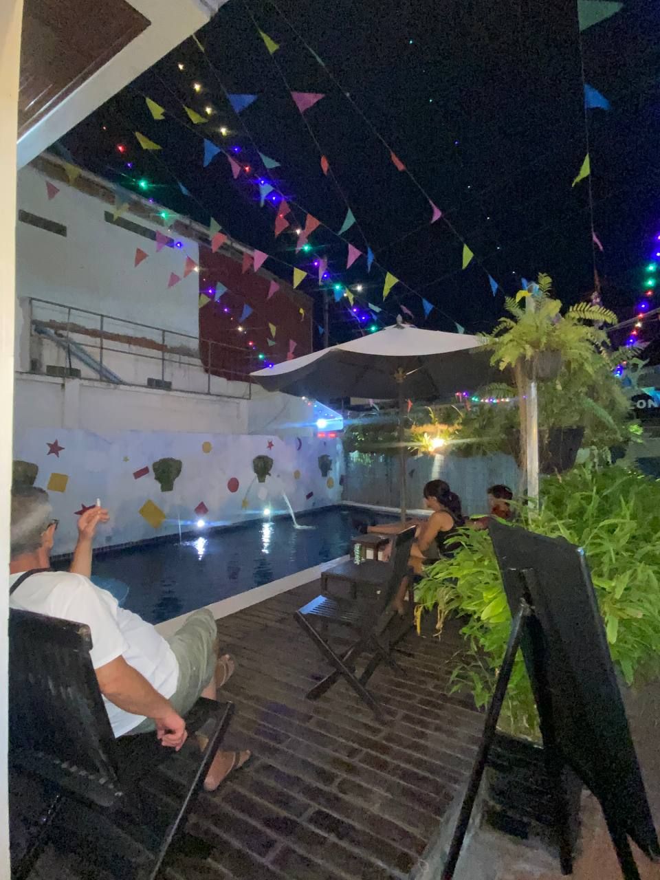 A poolside area with a pool, umbrellas, and seating.