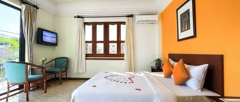 A hotel room with a bed, a TV, a window with curtains, a chair, and a table.