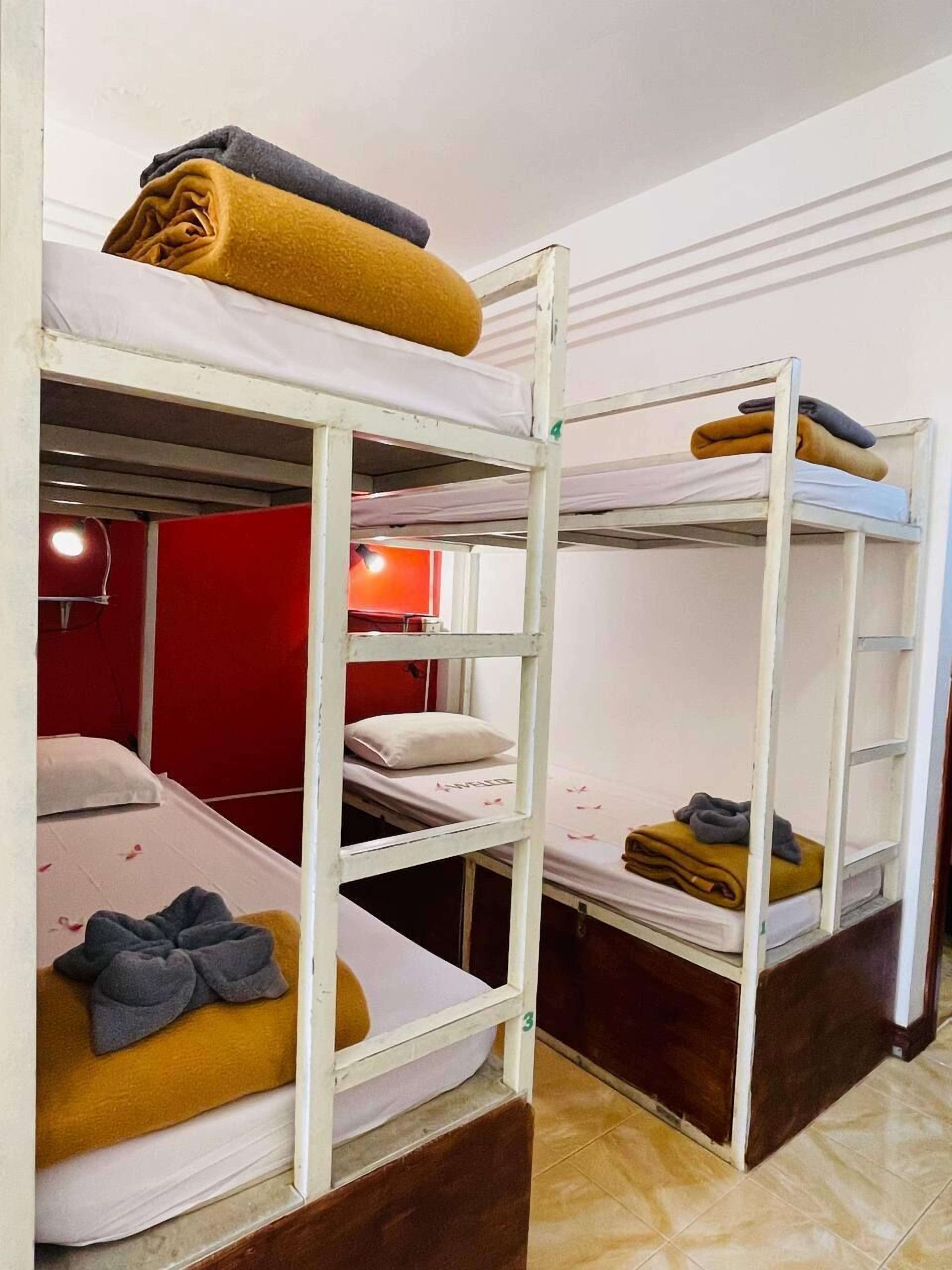Un dormitorio con literas, cada una con una almohada y un edredón enrollado.