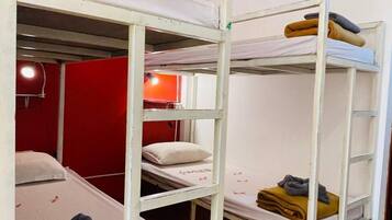 Un dormitorio con literas, cada una con una almohada y un edredón enrollado.