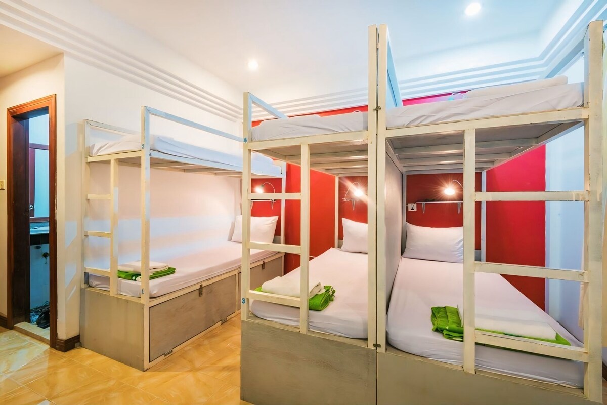 A room with bunk beds, a door, and a red wall.