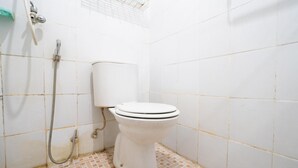 A small bathroom with a toilet, a shower, and a tiled floor. - OYO 94238 The Suite Metro Apartment By Riz Living (Bandung)