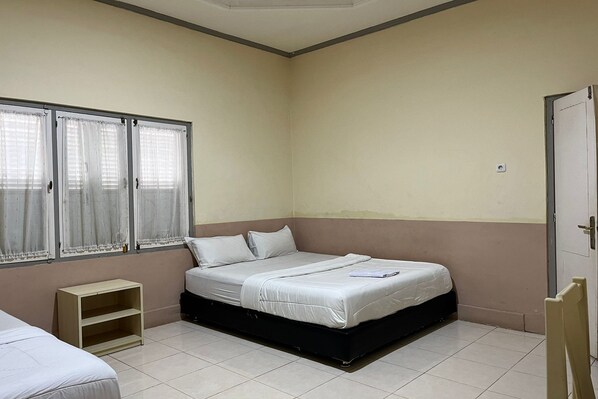 A bedroom with a single bed, a small wooden shelf, and a window with curtains. - Capital O 94240 Asoka Syariah (Padang)