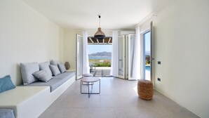 A modern interior with a sofa, a small table, and a view through a glass door to an outdoor area.