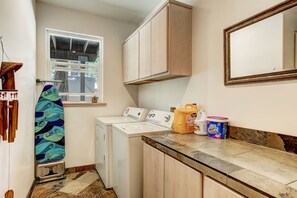 A laundry area with a washing machine, a drying rack, and cleaning supplies.