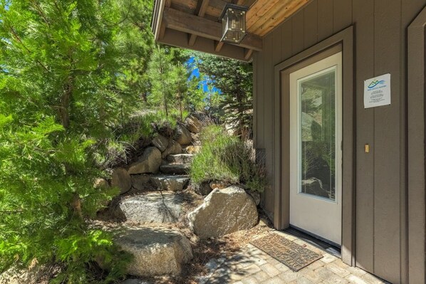 A wooden building with a stone staircase leading to a door with a window.