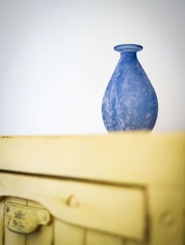 A blue vase on a surface with a plain background.