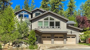 A two-story house with a garage, surrounded by trees and a clear sky.