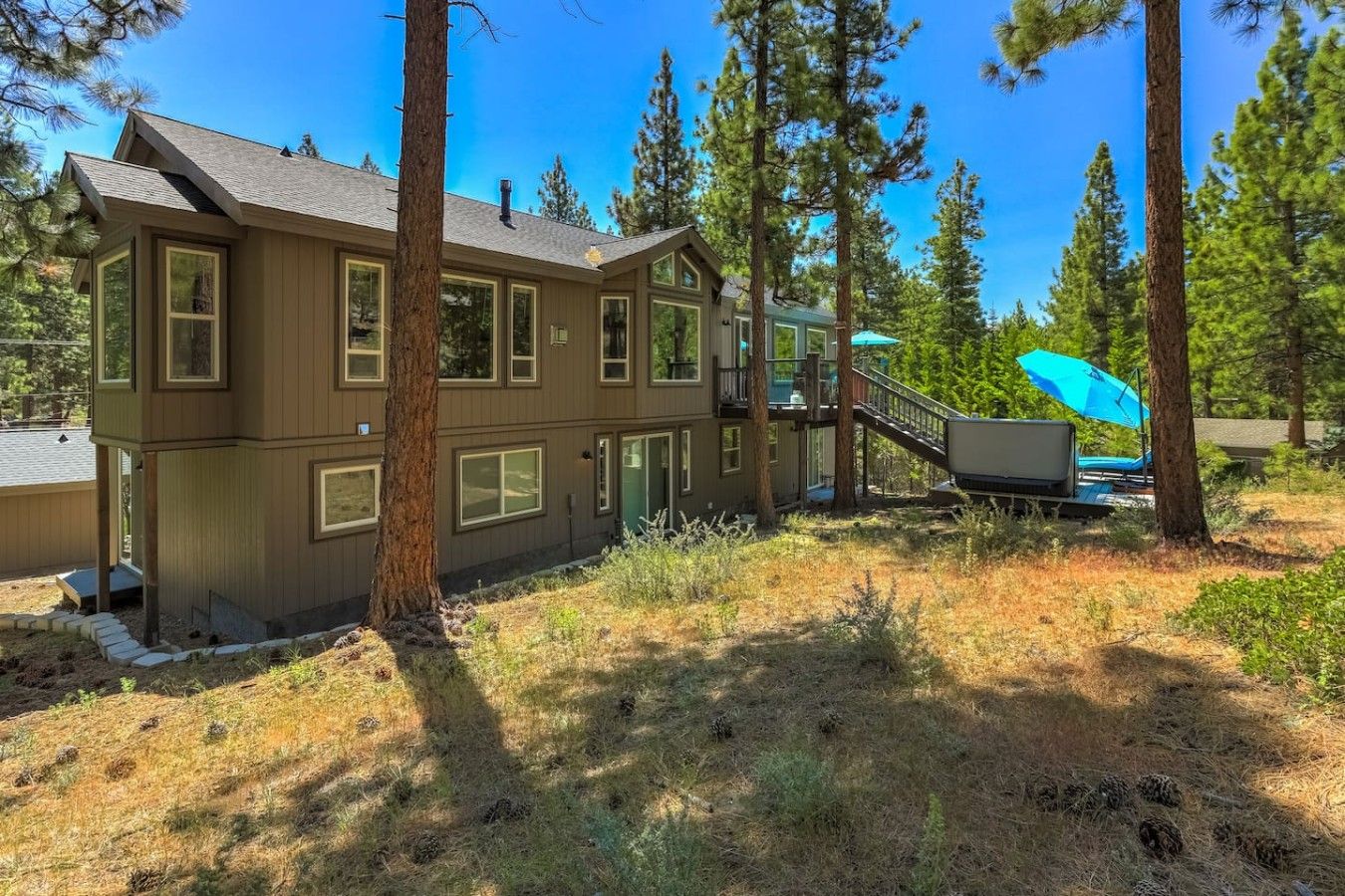 A two-story house with a deck and a staircase leading to a covered outdoor area.