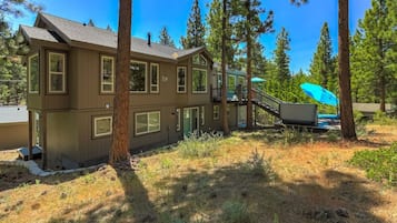 A two-story house with a deck and a staircase leading to a covered outdoor area.