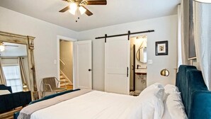 A bedroom with a bed, a ceiling fan, a wardrobe, a mirror, and a bathroom with a sink and a shower. - Modern Rustic 3 -bedroom 2 Bathrooms Carport (Oklahoma City)